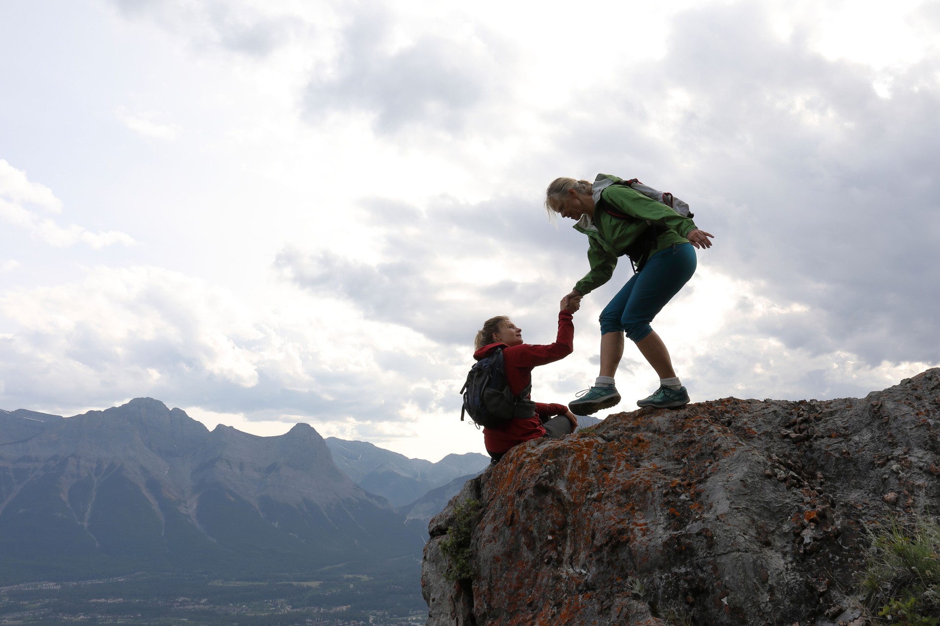 Female climbers helping each other up a mountain Female climbers helping each other up a mountain